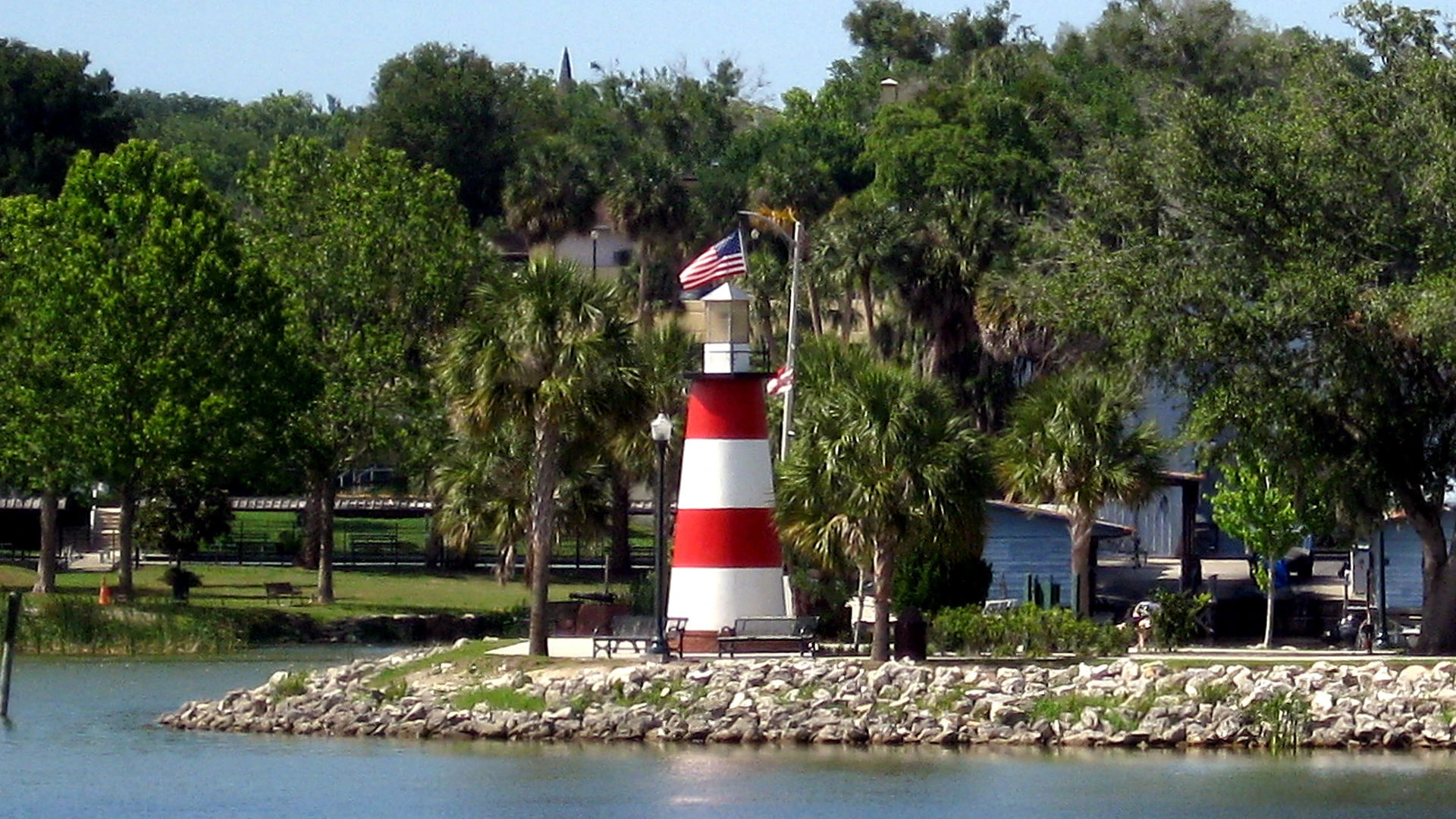 Red and white striped lighthouse on the Mount Dora lakefront, framed by palms and oaks